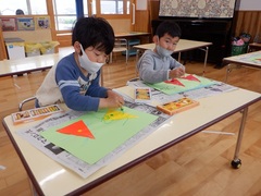 折り紙製作に絵を描いている幼児の写真