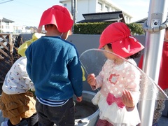 園庭で水が凍っているのを見付けた幼児の写真