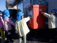 郵便局にあるポストを見ている幼児の写真