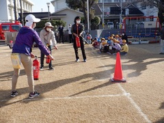 避難訓練で消火訓練をする教師の写真