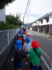 園外保育で公園まで歩いている幼児の写真