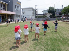 スプリンクラーを使って水遊びをする幼児の写真