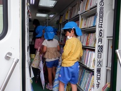 移動図書館で絵本を借りている幼児の写真