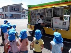 移動図書館つばき号で絵本を借りる幼児の写真