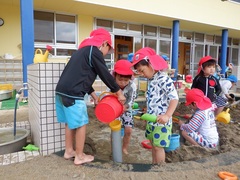 砂場で水を流して遊んでいる写真