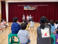 ホールでの音楽会ごっこで歌や踊りをしているいる幼児の写真