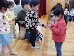 お別れ会でプレゼントを渡す幼児の写真