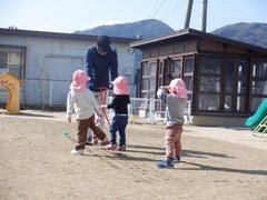 芝生のお手入れの様子を見ている幼児の写真