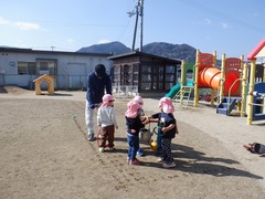 芝生のお手入れの様子を見ている幼児の写真