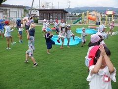 園庭で水遊びをする幼児の写真