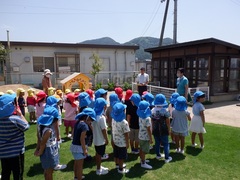 避難訓練で芝生園庭に並ぶ幼児の写真