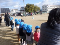 小学校のマラソン大会の応援をする幼児の写真