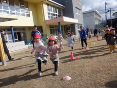 園庭でマラソンをする幼児の写真