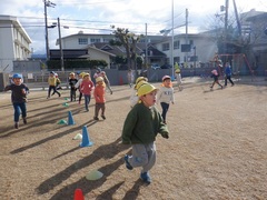 園庭でマラソンをする幼児の写真