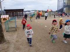 園庭でマラソンをする幼児の写真