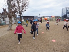 園庭でマラソンをする幼児の写真