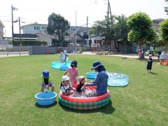 芝生園庭で水遊びをする幼児の写真