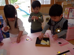 こいのぼりにシールを貼って製作をする幼児の写真