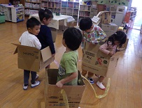 段ボール箱で作った電車でごっこ遊びをする幼児たち