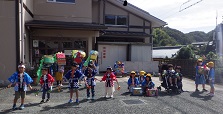 公民館の前で踊りを披露する幼児と獅子と太鼓をする小学生