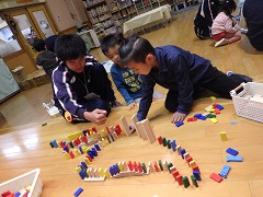 ドミノで遊ぶ幼児と中学生