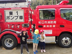 消防・ポンプ車の前でポーズする幼児