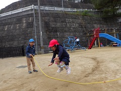 5歳児が長縄を持ち、4歳児が跳ぶ様子