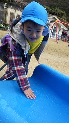 すべり台の水滴の氷を触る幼児