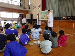 移動動物園で獣医さんの話を聞く幼児と児童