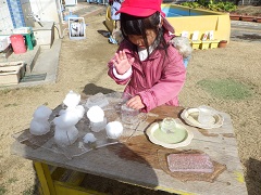 大きな氷の上に雪だるまや氷をのせて飾る幼児