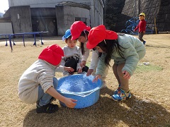 たらいの上に氷を置き、テーブルを作る幼児たち