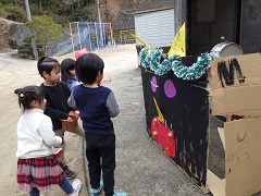 作った鬼が島に向けて豆まきをする幼児