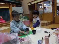 ひな人形を作る幼児とそれを見る幼児