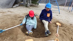 穴の上に座り、会話する幼児