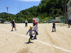 運動場で小学生と走る幼児