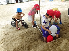 砂遊びをする小学生を見る幼児