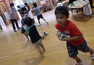 玉をいっぱい持って玉入れをする幼児