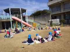 園庭で弁当を食べる幼児たち