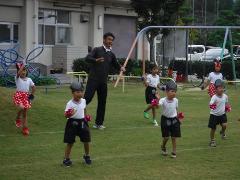 芝生で踊る幼児と園長先生