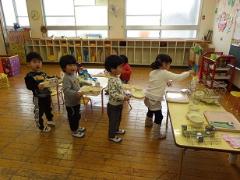 給食の片付けをする幼児