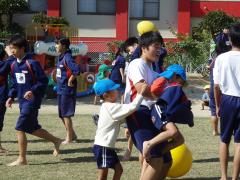 芝生の上で中学生と遊んでいる幼児の様子