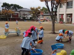 砂場の玩具を片付ける幼児の姿