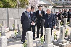 写真：ロシア人墓地保存会会長から説明を受ける駐日ロシア大使と松山市長