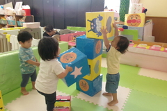 大きなアンパンマンブロックを積み上げている子どもたちの写真