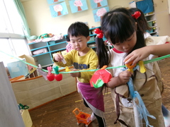 洗濯ばさみで折り紙のいちごをつるす子どもたちの写真