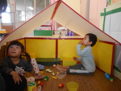 手作りの家の中でままごとをする子どもたちの写真