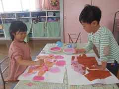 画用紙に貼った木の枝に桜を描く子どもたちの写真