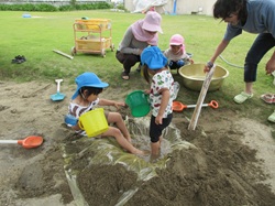 砂場でどろんこ遊びを楽しんでいる様子