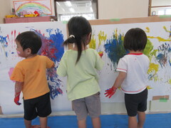 大きな紙に手で絵を描いている子どもたちの様子