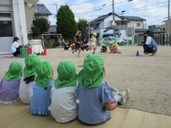 5歳児のリレーを見る子どもたちの写真